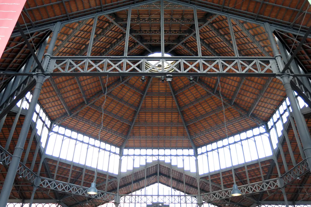 Looking up into the iron and glass roof of the former Mercat del Born with red-tiled panels and high windows